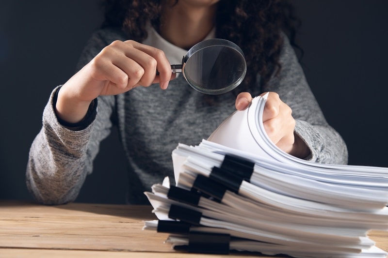 a woman with a magnifying glass looking at documents