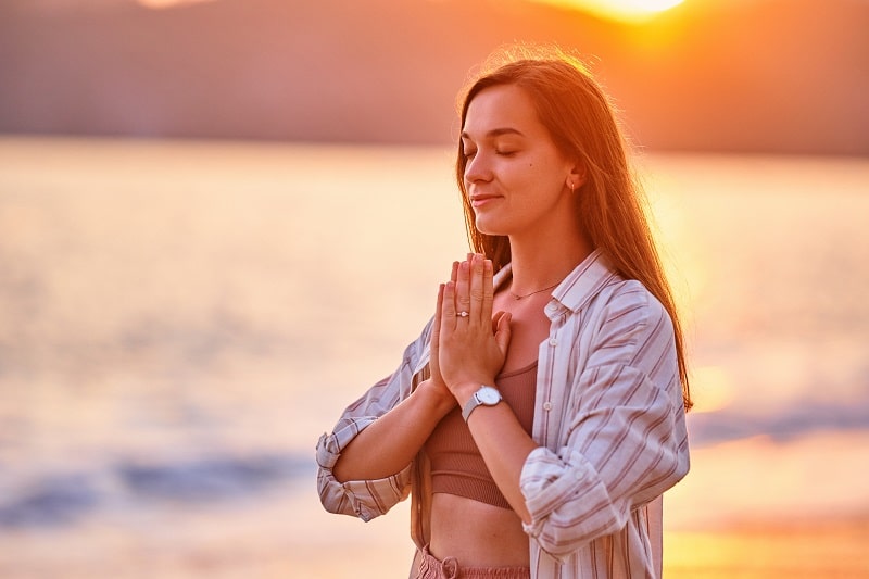 a woman praying in the sunset